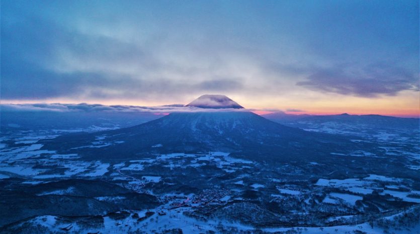 Mt Yotei breaks through the clouds as the sun rises behind